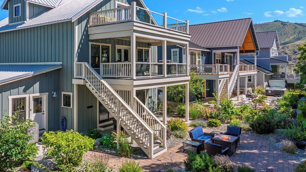 Ein mehrstöckiges Haus mit einem Balkon, einer Treppe und einer Terrasse mit Gartenmöbeln.