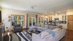 Ein geräumiges Wohnzimmer mit einer Eckcouch, einem Glastisch und einem Streifenmuster-Teppich.