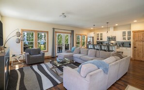 Ein geräumiges Wohnzimmer mit einer Eckcouch, einem Glastisch und einem Streifenmuster-Teppich.