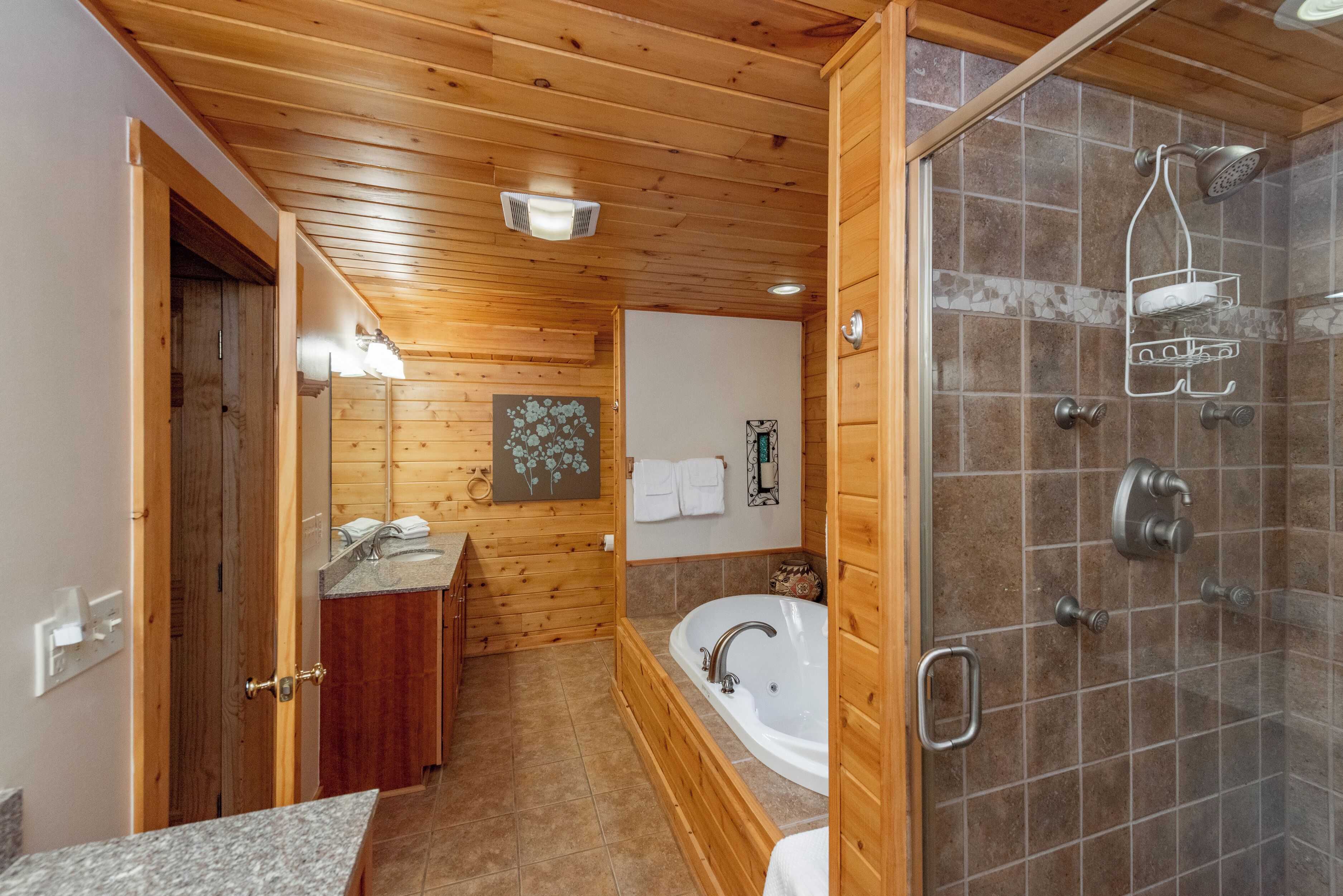 Ein Badezimmer im Holzdesign mit Dusche, Badewanne und Schminktisch.