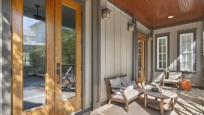 A covered porch with a bench, a table, and a door with glass panels.