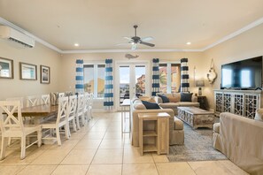 A spacious living area with a dining table, sofas, a TV, and a ceiling fan.