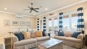 A living room with two beige sofas, a wooden coffee table, and a ceiling fan. - 🌞 4.5 Bedroom 3 Bath townhome with 2 community pools 🏖️ (Pensacola Beach)
