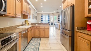 A modern kitchen with wooden cabinets, stainless steel appliances, and a central island. - 🌞 4.5 Bedroom 3 Bath townhome with 2 community pools 🏖️ (Pensacola Beach)