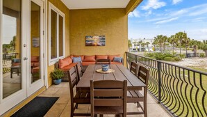 A balcony with a dining table, chairs, and a sofa with cushions. - 🌞 4.5 Bedroom 3 Bath townhome with 2 community pools 🏖️ (Pensacola Beach)