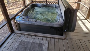 A hot tub under a wooden deck with a view of a forested area. - 'Just a Step Away' - a Secluded Cabin on Stover Creek w/Fiber Wi-Fi & Hot Tub (Ellijay)