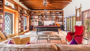 Ein gemütliches Wohnzimmer mit Billardtisch, bequemen Sofas und einem roten Sessel.