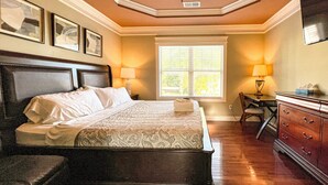 Une chambre d’hôtel avec un grand lit, un bureau, une commode et une fenêtre avec des stores.