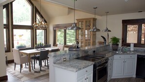 Une cuisine moderne dotée d’un grand îlot central, de meubles encastrés et de luminaires suspendus.