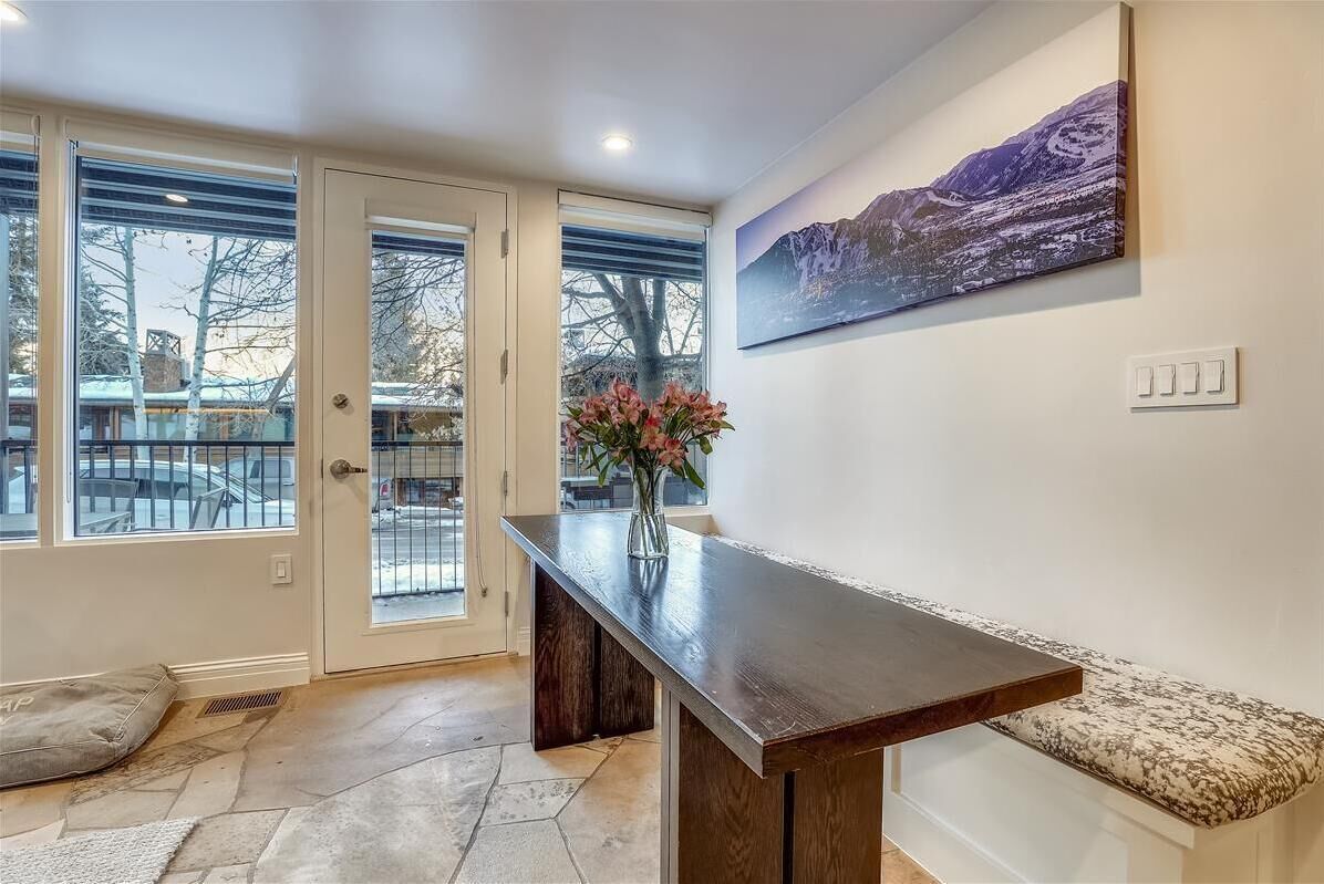 A modern interior with a wooden bench, a vase with flowers, and a mountain landscape painting on the wall.