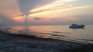 A boat on calm waters during sunset. - Smart Home, direct Beach Dunes Nat’l Park access, Hot Tub, luxury amenities (Miller Beach)