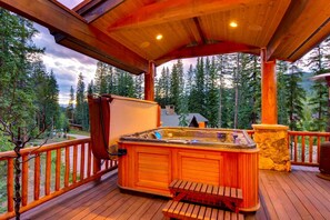 A wooden deck with a hot tub, wooden benches, and a stone planter. - Alders Chalet: Lux Retreat w/ Private Hot Tub, Sauna, Theater, Pizza Oven (Keystone)