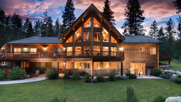A large, two-story log cabin with a balcony, surrounded by a well-maintained lawn and trees. - Beautiful Secluded Log Home 5 minutes from town. (Hamilton)