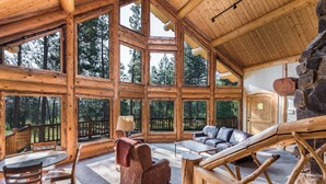 A spacious log cabin with large windows, a wooden dining area, and a lounge with a stone fireplace. - Beautiful Secluded Log Home 5 minutes from town. (Hamilton)