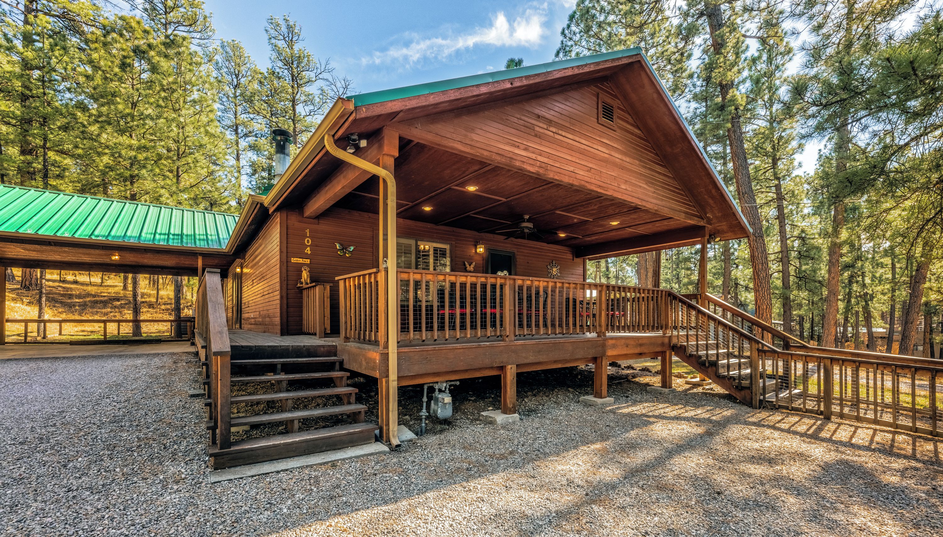 A cabin with a wooden exterior, a covered porch, and a staircase leading to the entrance.