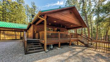 A cabin with a wooden exterior, a covered porch, and a staircase leading to the entrance.
