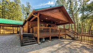 A cabin with a wooden exterior, a covered porch, and a staircase leading to the entrance.