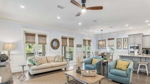 A spacious living room with a sofa, armchairs, a coffee table, and a ceiling fan.
