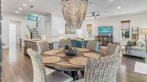 A dining area with a round wooden table, woven chairs, and a chandelier.