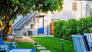 A backyard with a patio area, a grill, and a staircase leading to a door. - City Haven (Burbank)