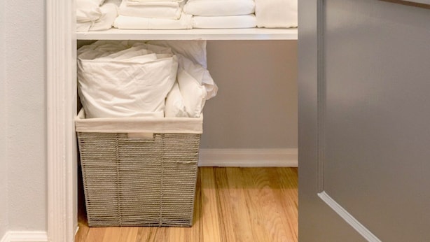 A closet with shelves holding folded towels and a basket. - City Haven (Burbank)
