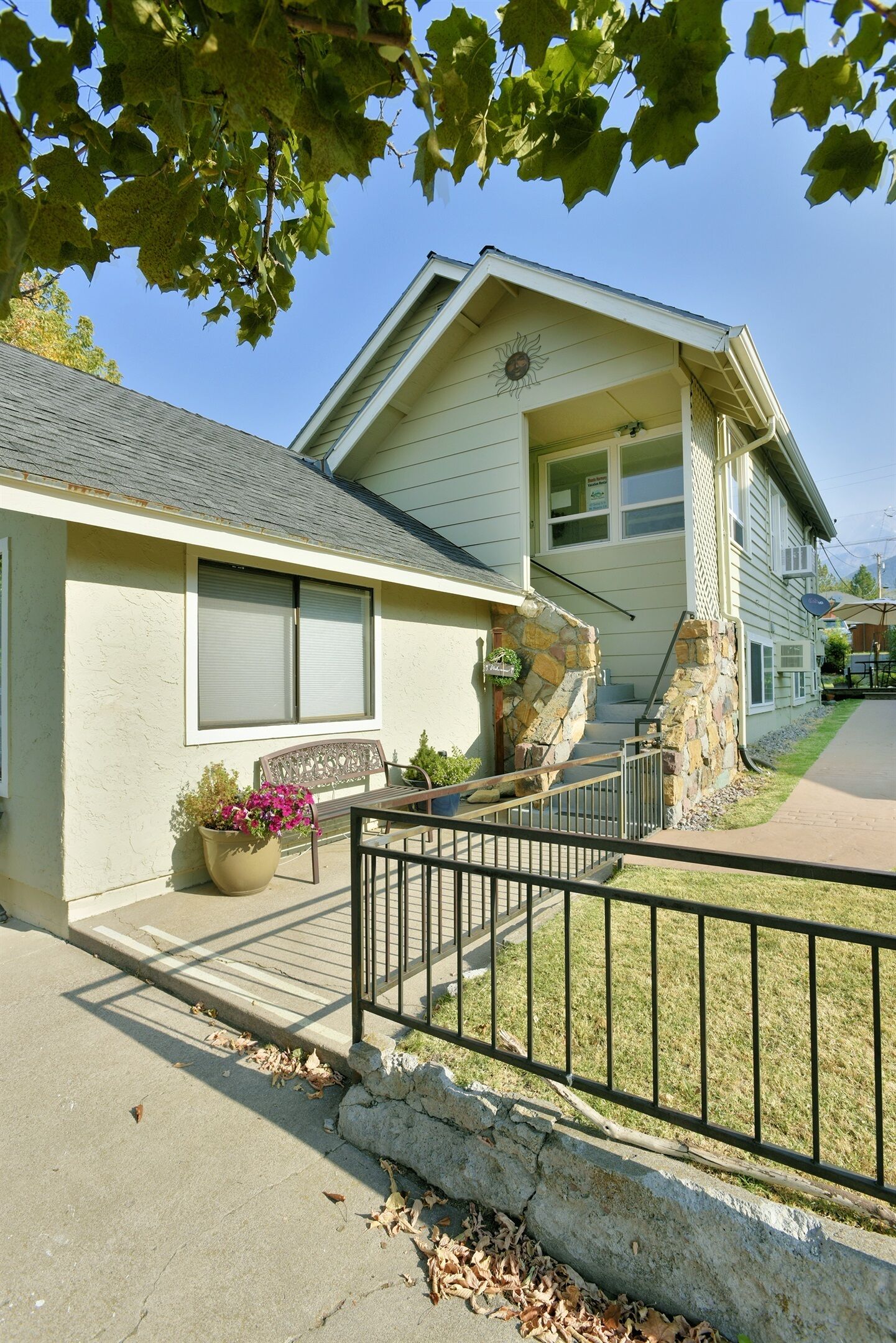 A two-story house with a stone staircase, a front porch with a bench, and a garage.