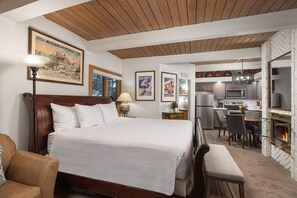A hotel room with a large bed, a desk, a kitchenette, and a fireplace. - Aspenwood L3 - Ski, Soak, Relax | Cozy Mountain Stay, Walk to Slopes (Snowmass Village)