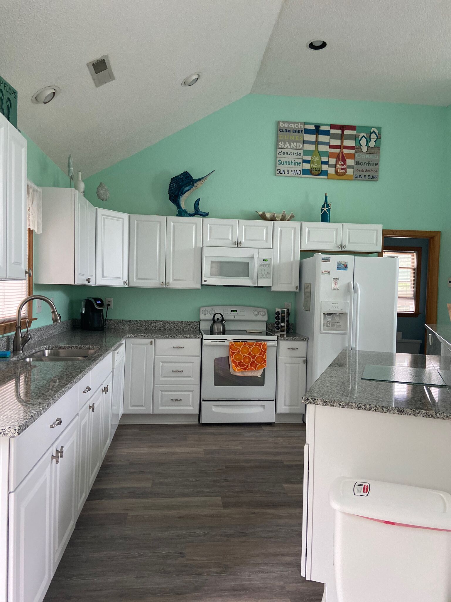 A kitchen with white cabinets, a microwave, an oven, and a refrigerator.