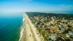 An aerial view of a coastal residential area with houses, a beach, and a clear sky. - Beach Oasis. 2 Mins to Priv Beach&4X4 beach.Hottub.Foosball.Close to shop/dining (Corolla)