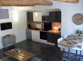 Une cuisine compacte avec des meubles de couleur sombre, un plan de travail en bois et un four à micro-ondes moderne.