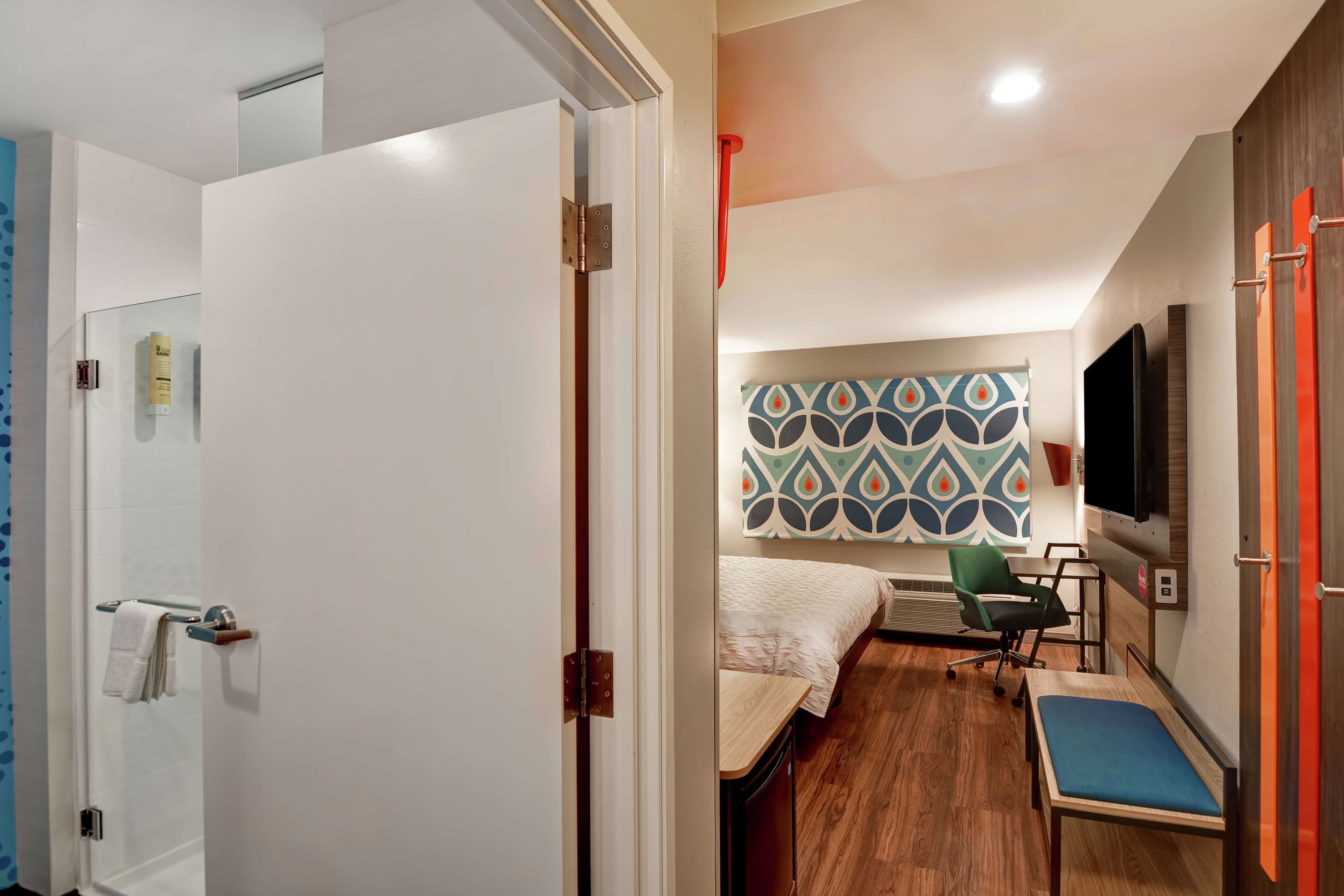 Une chambre d’hôtel comprenant un lit, un bureau, une chaise, une télévision et un espace douche.