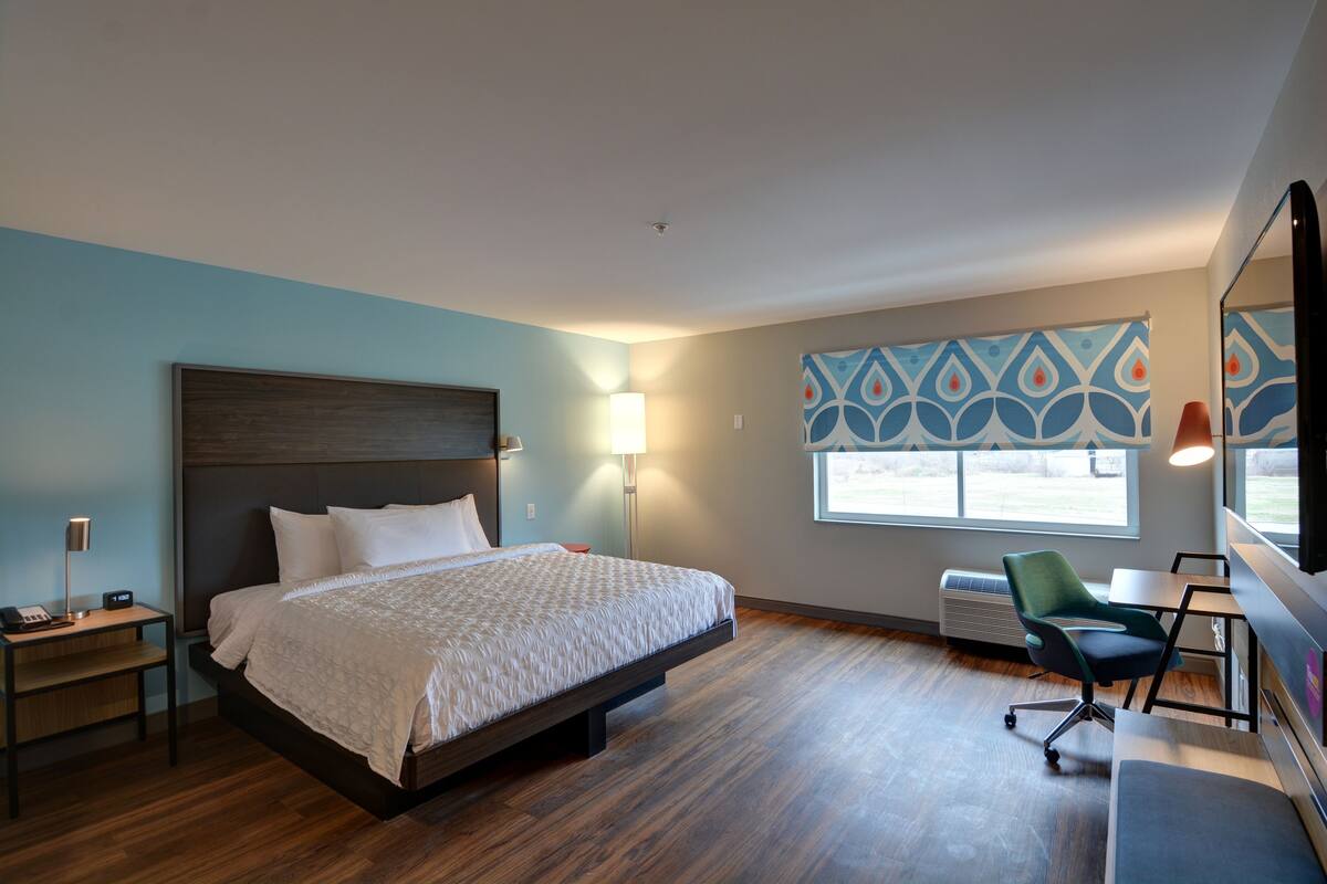 A modern hotel room with a large bed, bedside tables, a desk, and a chair.