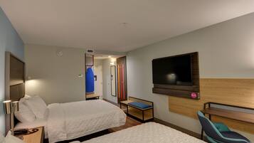 Habitación de hotel con dos camas, televisión montada en la pared, un escritorio y una silla.