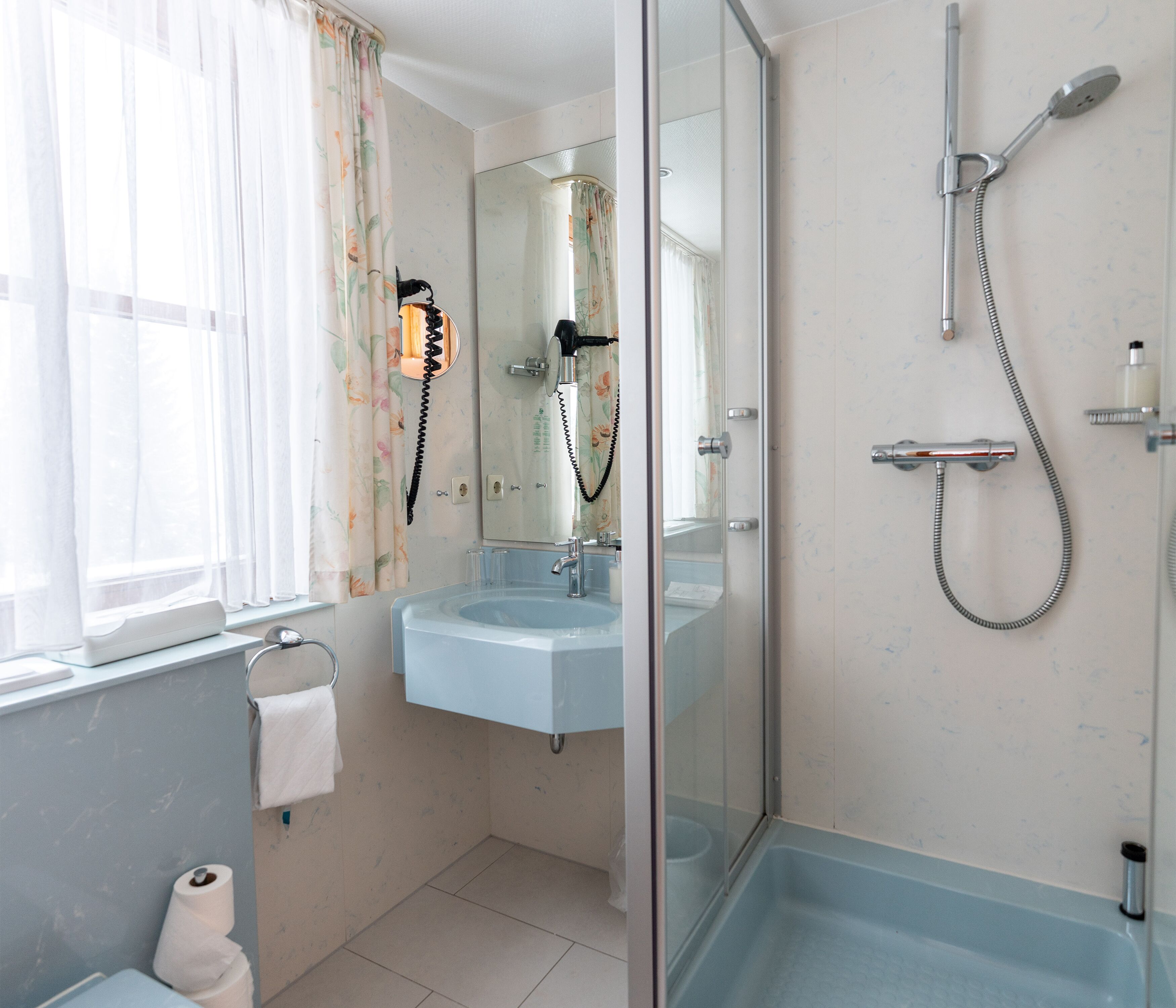 A bathroom with a glass-enclosed shower, a sink, and a toilet.