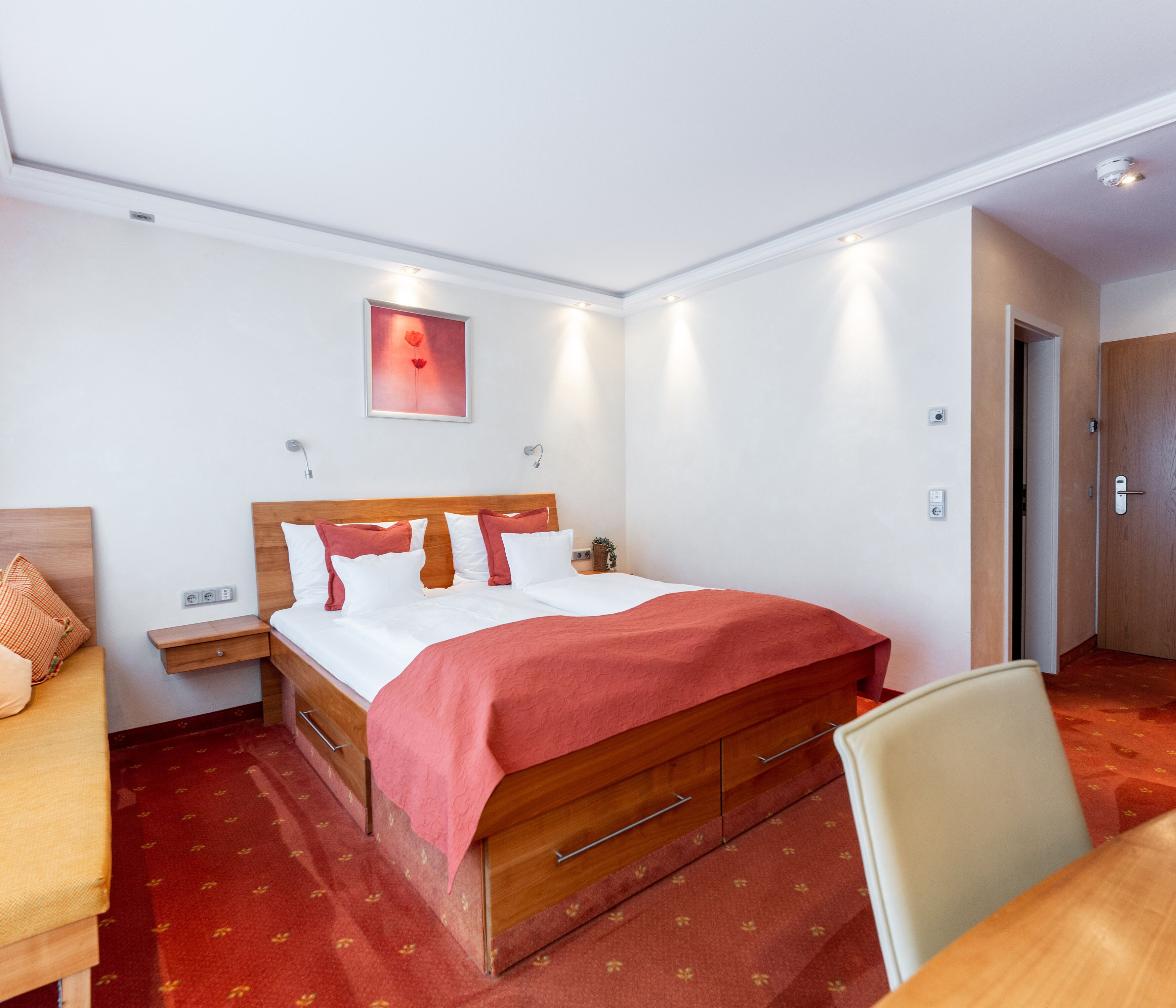 Una habitación de hotel con una cama de madera, una mesita de noche, un escritorio y una silla.