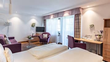 A hotel room with two beds, a desk, a chair, a TV, and a wardrobe.