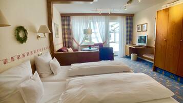 A hotel room with two beds, a desk with a computer, a TV, and a view of the outside.