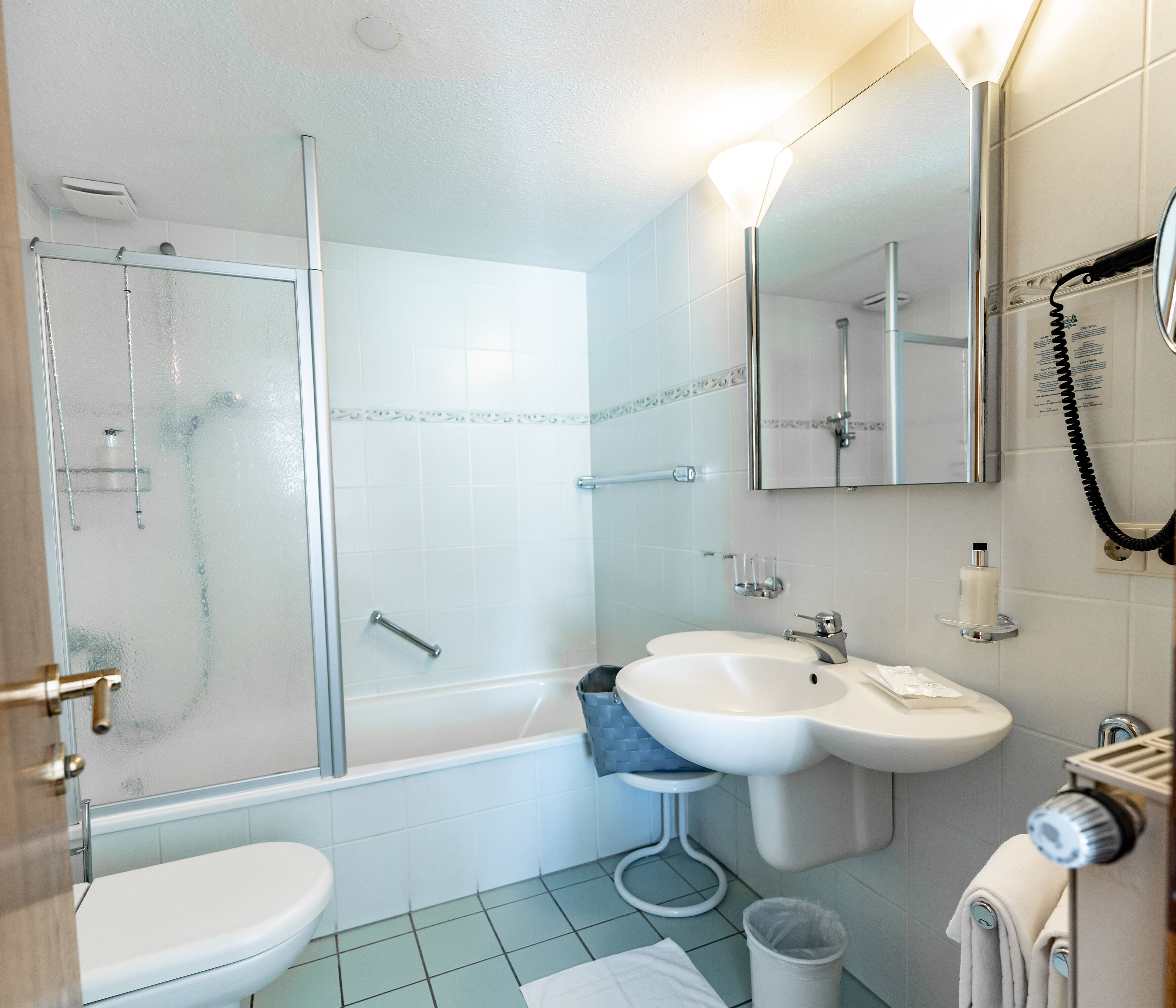 Un baño moderno con ducha de vidrio, lavamanos, inodoro y espejo.