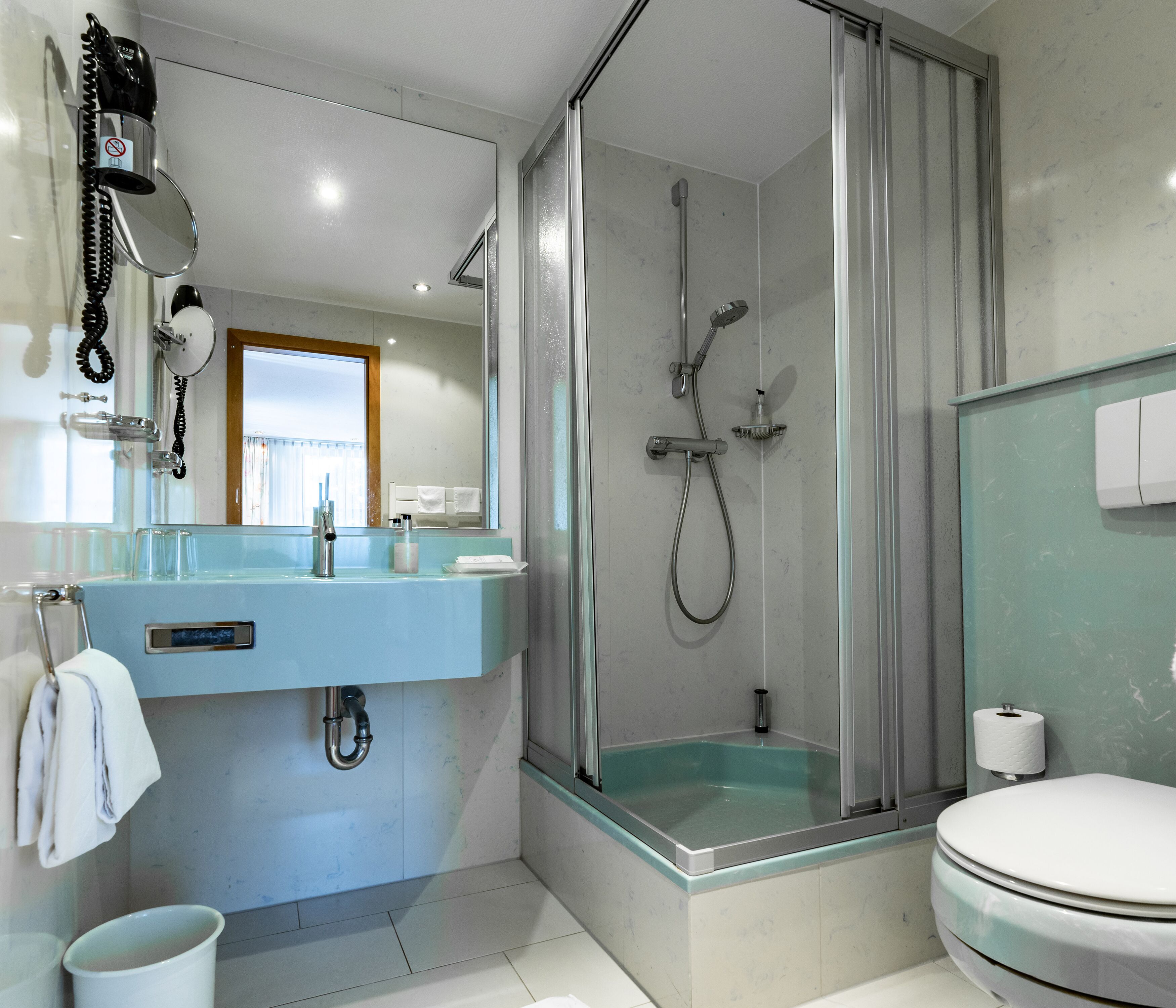 Une salle de bain moderne avec une douche à parois de verre, un lavabo avec un miroir et des toilettes.