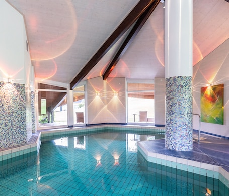 Una piscina techada, sillones reclinables de piscina