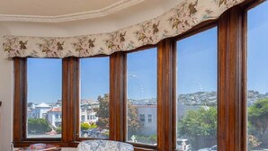 Una habitación con ventanas amplias, una silla de madera y una mesita.
