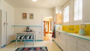 Una cocina con una mesa de comedor, sillas, cafetera y licuadora.