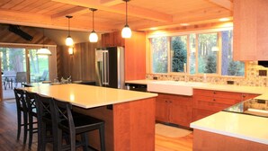 Une cuisine moderne dotée d’un grand îlot central, de meubles en bois et de luminaires suspendus.