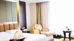Een hotelkamer met een groot bed, een stoel, een kleine tafel en een nachtkastje.