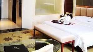Een hotelkamer met een bed, nachtkastje en een zithoek met een stoel.