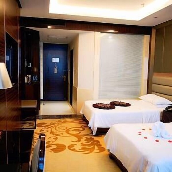 A hotel room with two beds, a bathroom, and a desk.