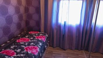 A room with a bed, a ceiling light, and a window with curtains.