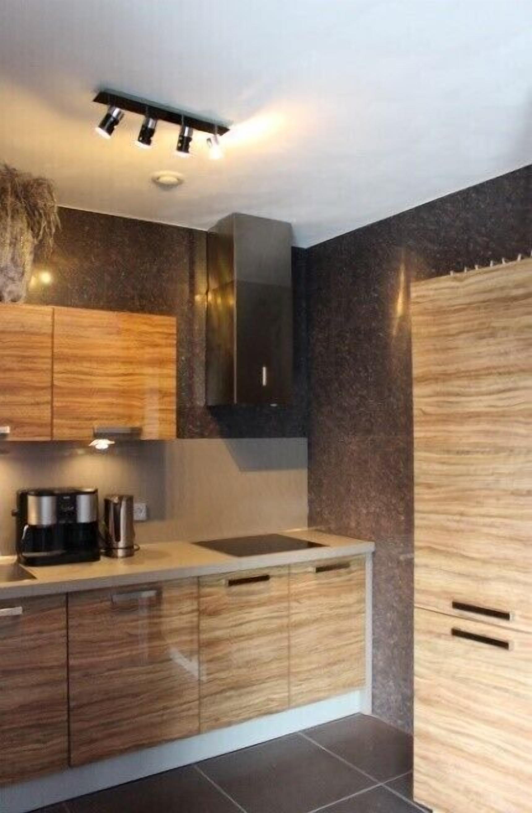 A modern kitchen with wooden cabinets, a built-in oven, and a coffee maker.
