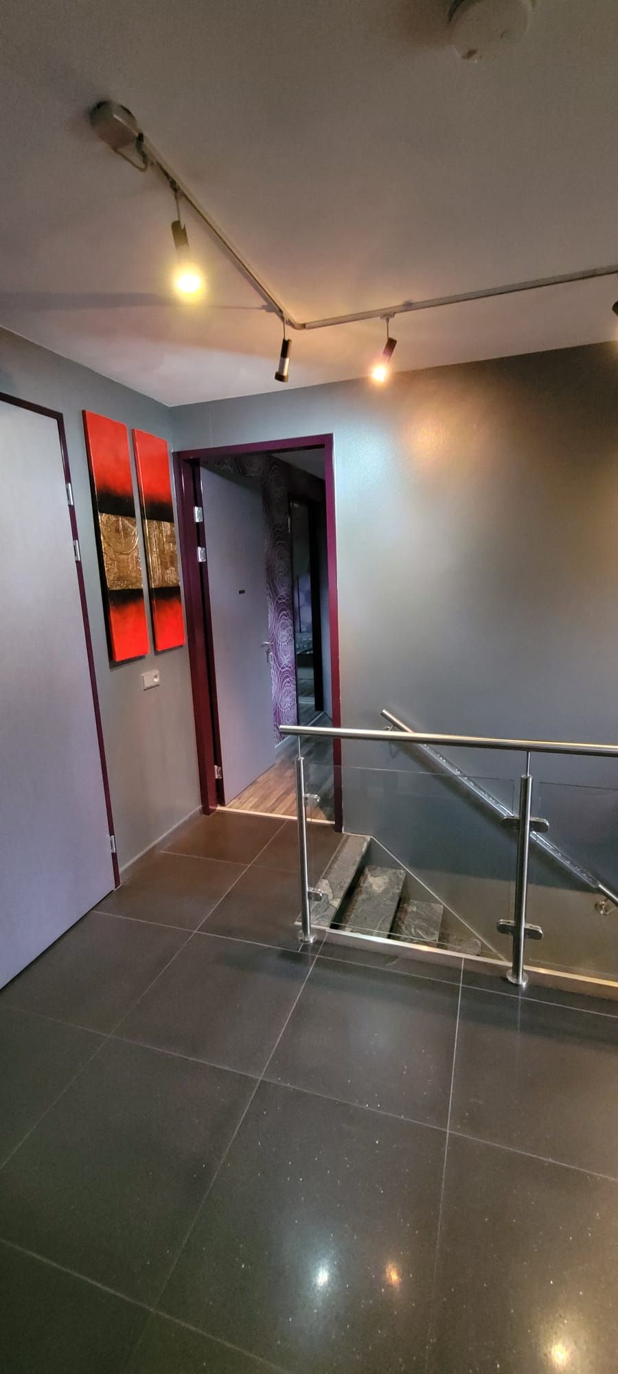 A modern interior with a staircase, metal handrails, and a ceiling light fixture.
