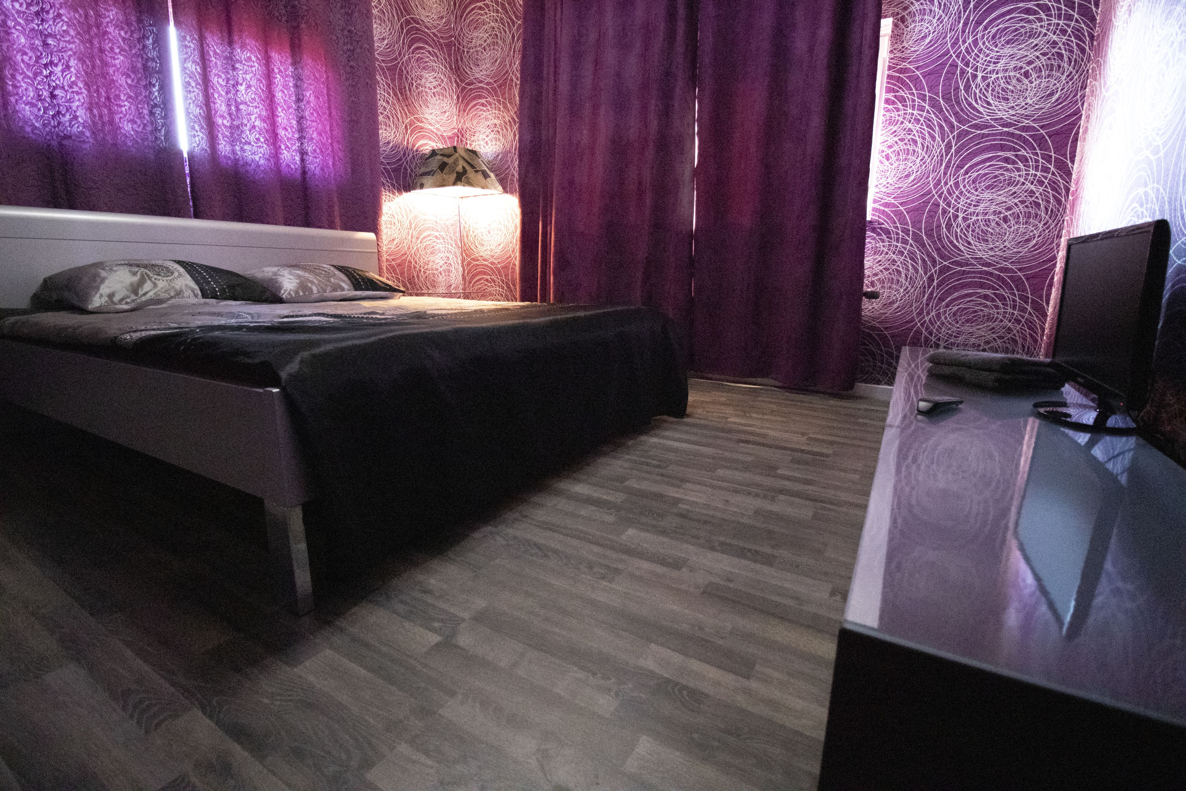 A bedroom with a bed, a desk, and a lamp.